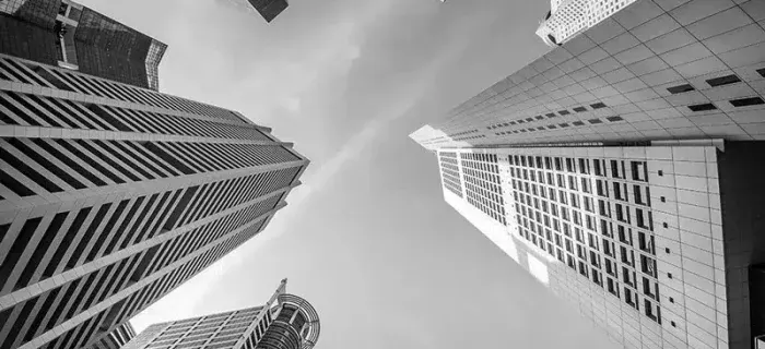 Fotografía en blanco y negro de varios rascacielos vistos desde el suelo, con el cielo al fondo
